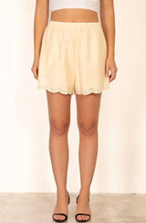 Flat-lay of the Relle Linen Shorts in yellow, showcasing scalloped hem and lightweight fabric.