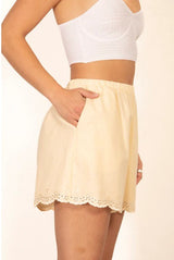 Side view of the Relle Linen Shorts in yellow, showing scalloped hem and side pockets.