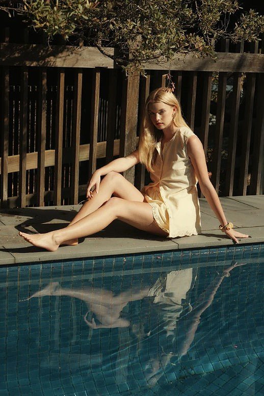 Relle Linen Shorts styled with the matching top, worn by a model seated beside a pool.
