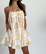 Woman wearing a yellow and white patterned dress on a plain background