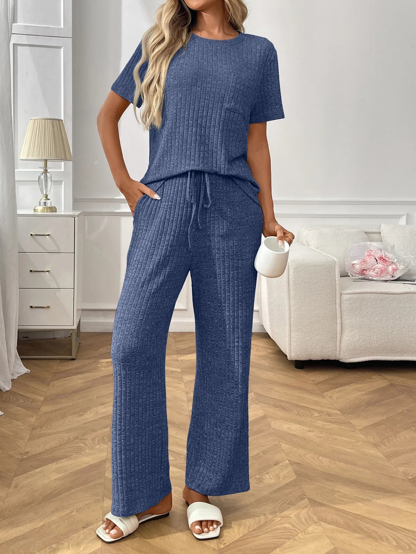 Woman wearing a blue  textured pants and top set in a living room setting