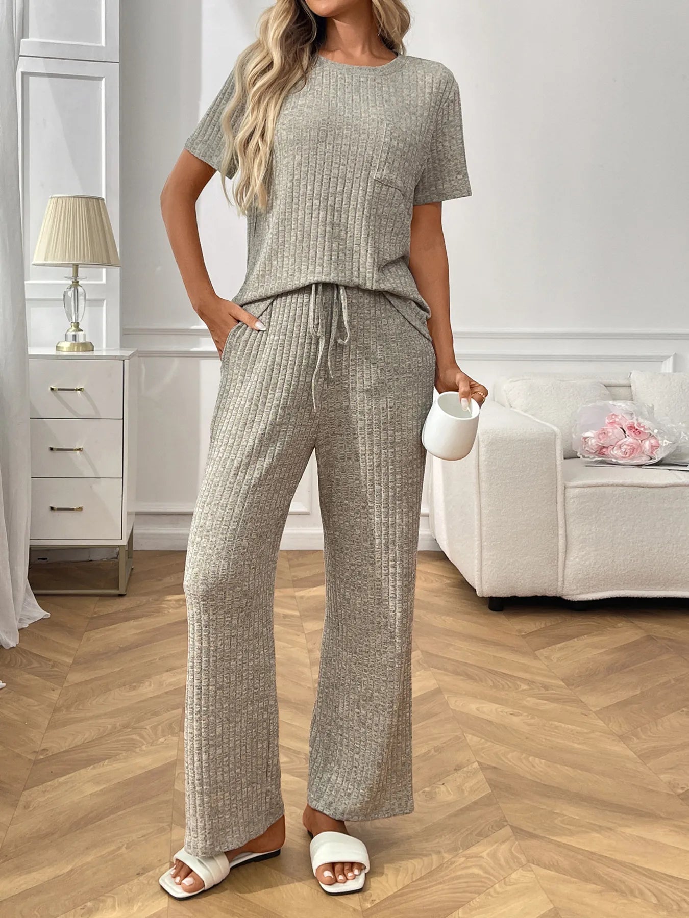 Woman wearing a  grey textured pants and top set  in a living room.