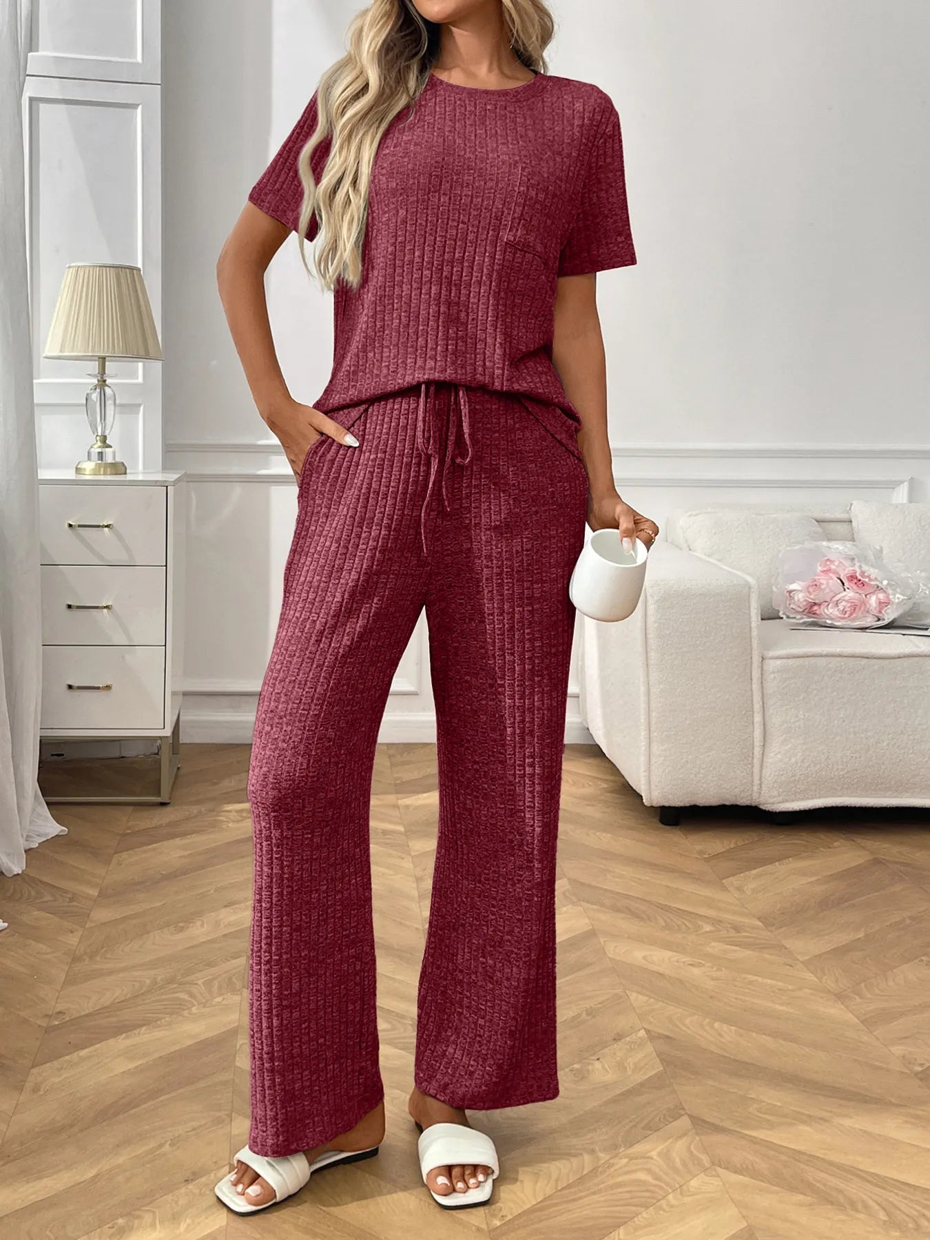 Woman wearing a burgundy  textured pants and top set in a living room setting