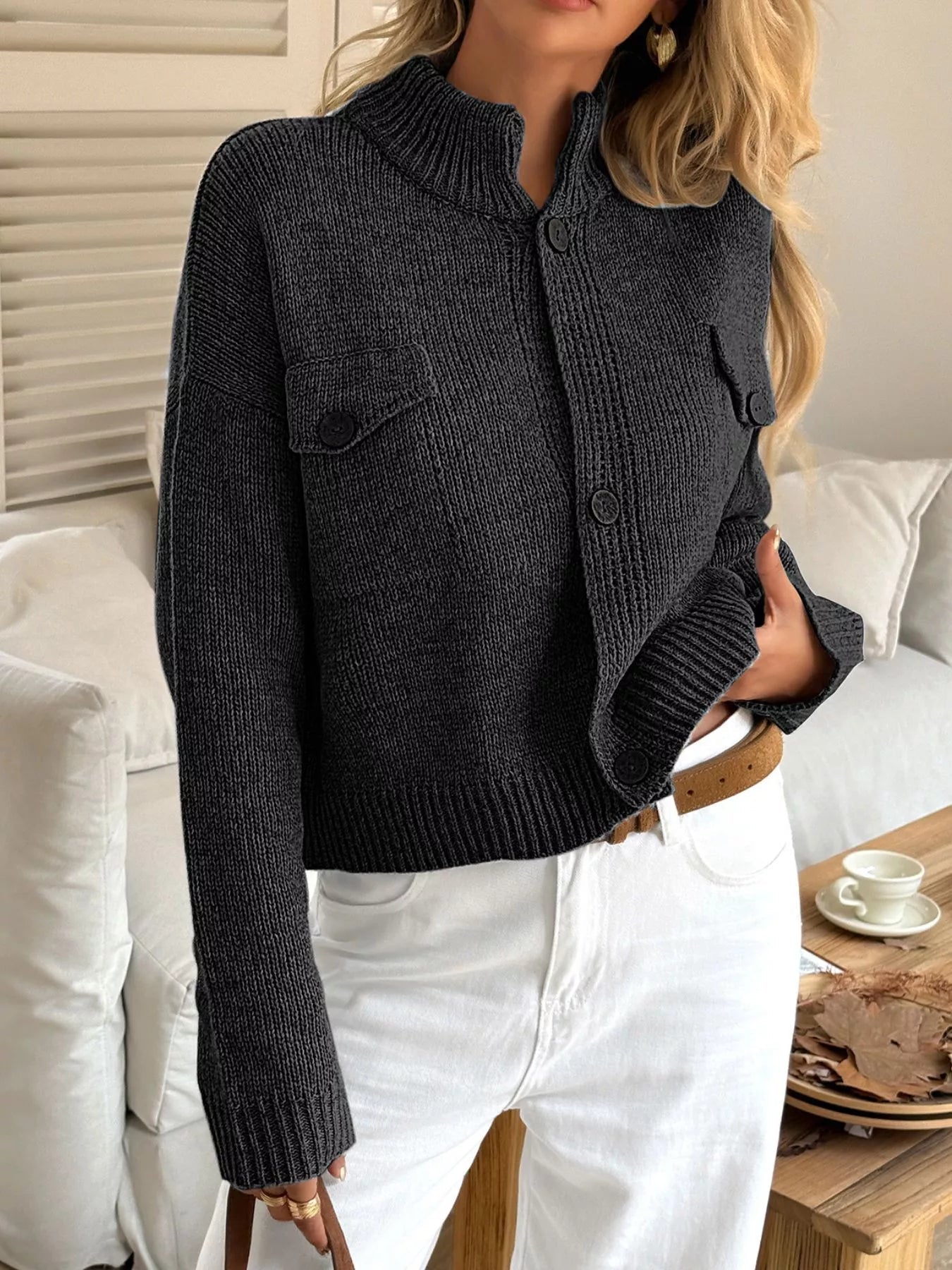 Person wearing a dark grey knitted cardigan in a casual setting.