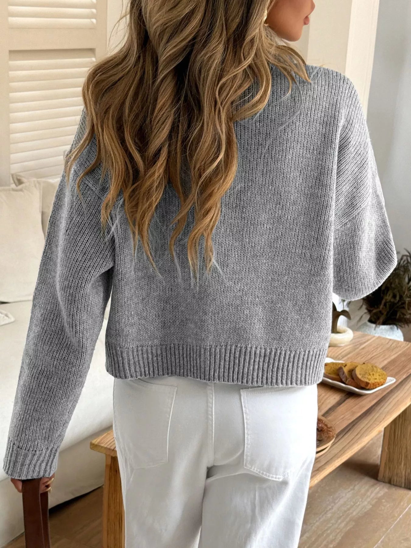 Person wearing a light blue sweater in a casual indoor setting