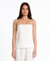 Woman wearing a white strapless top and pants on a white background