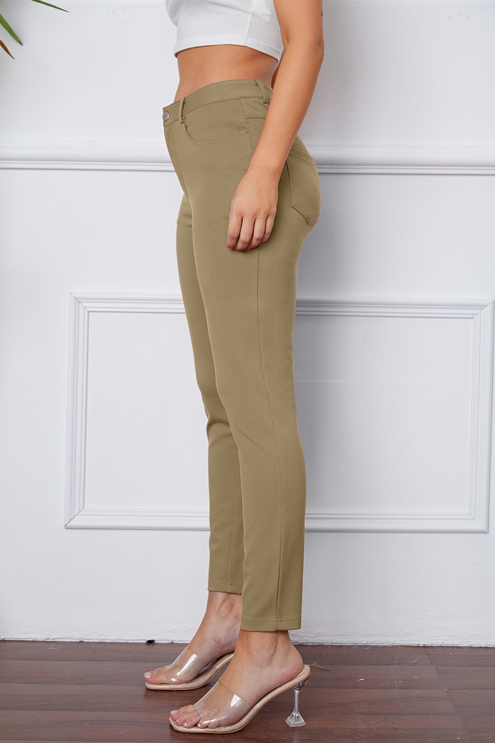 Person wearing olive green pants against a white wall