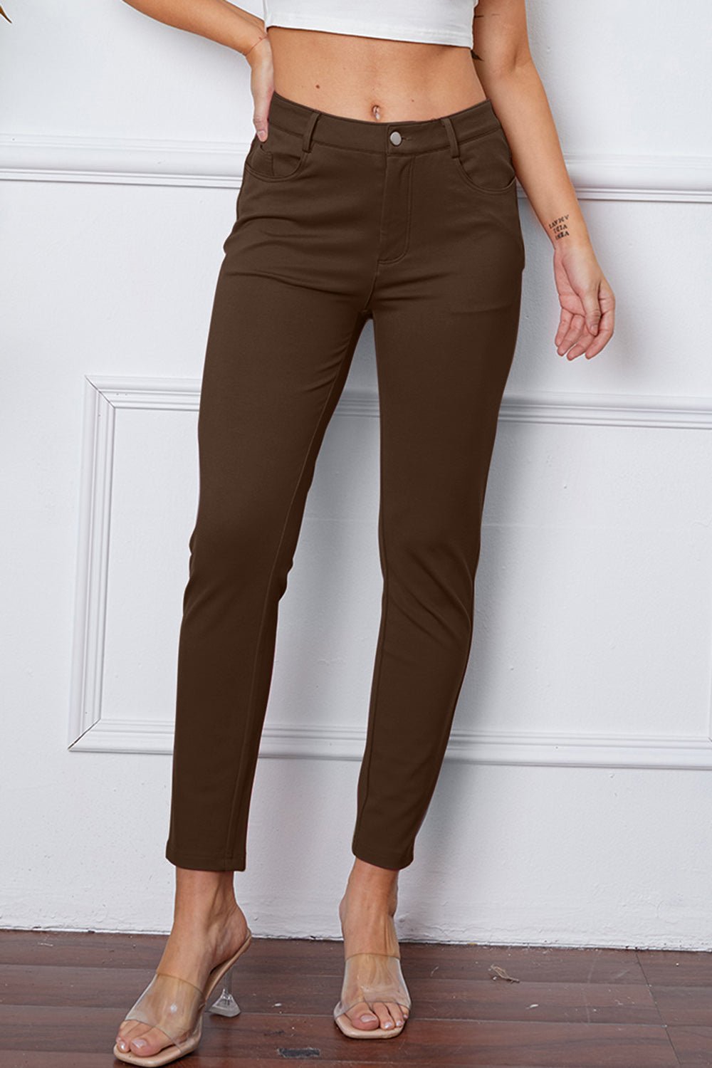 Brown pants worn by a person against a white wall.
