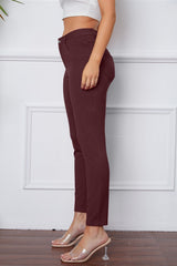 Burgundy pants worn by a person against a white wall.