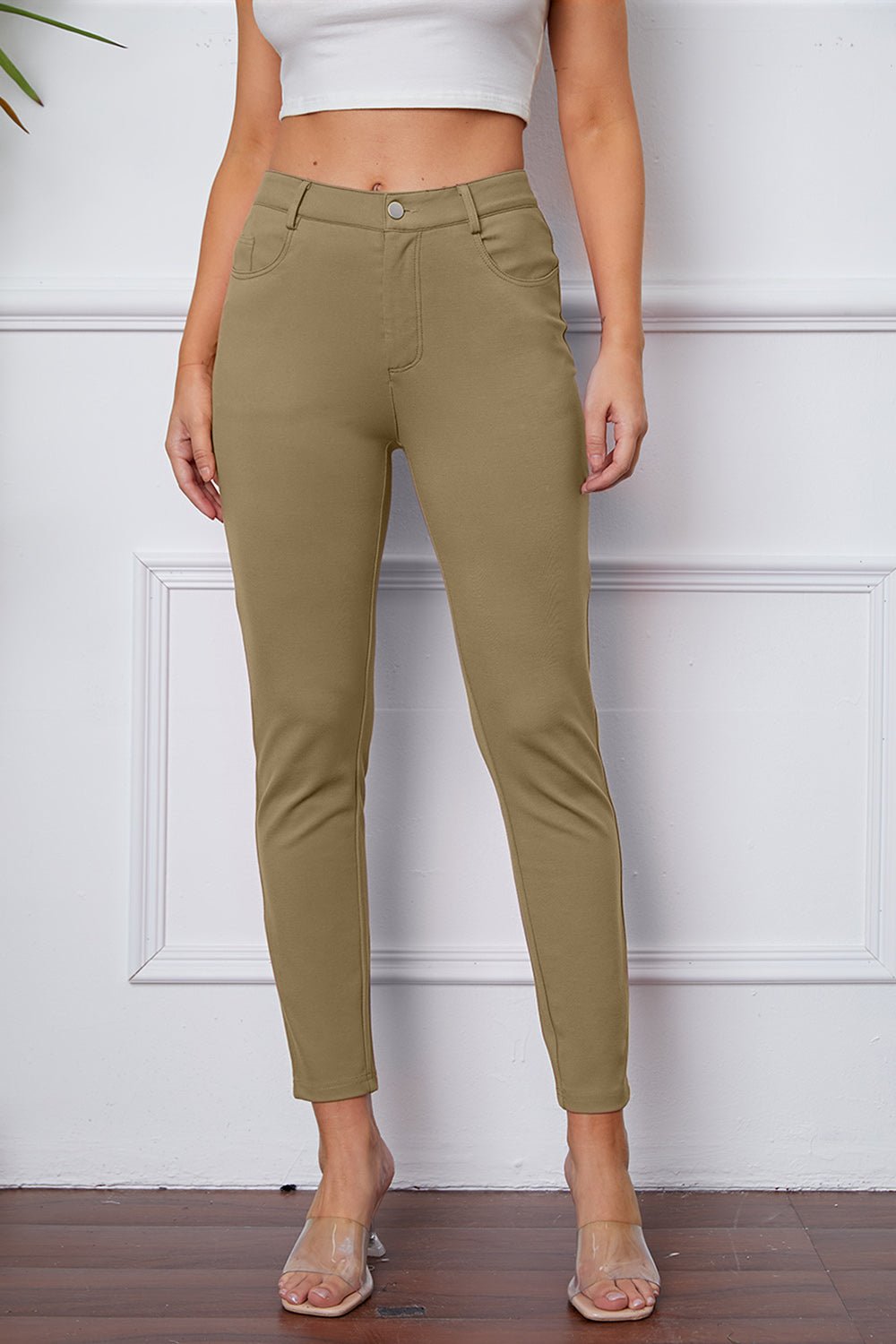 Person wearing olive green pants against a white wall