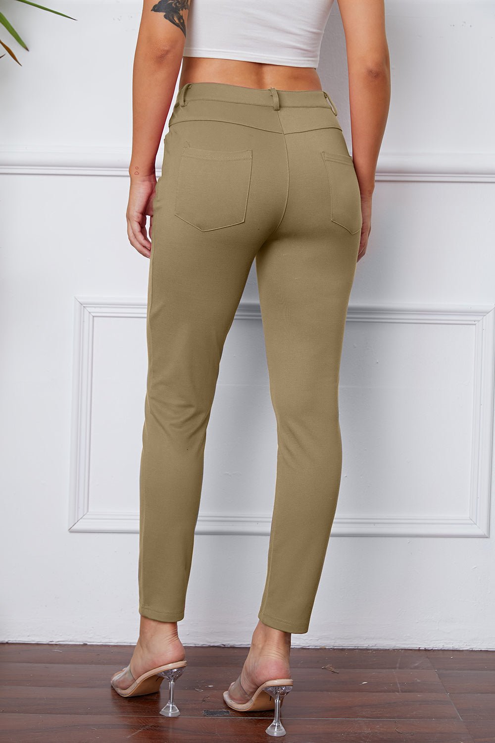 Person wearing olive green pants against a white wall