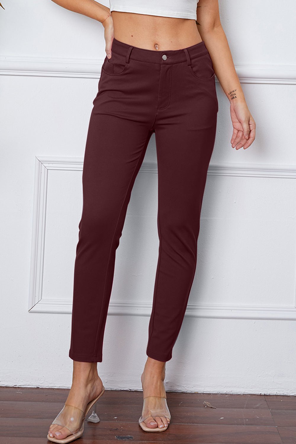 Burgundy pants worn by a person against a white wall.