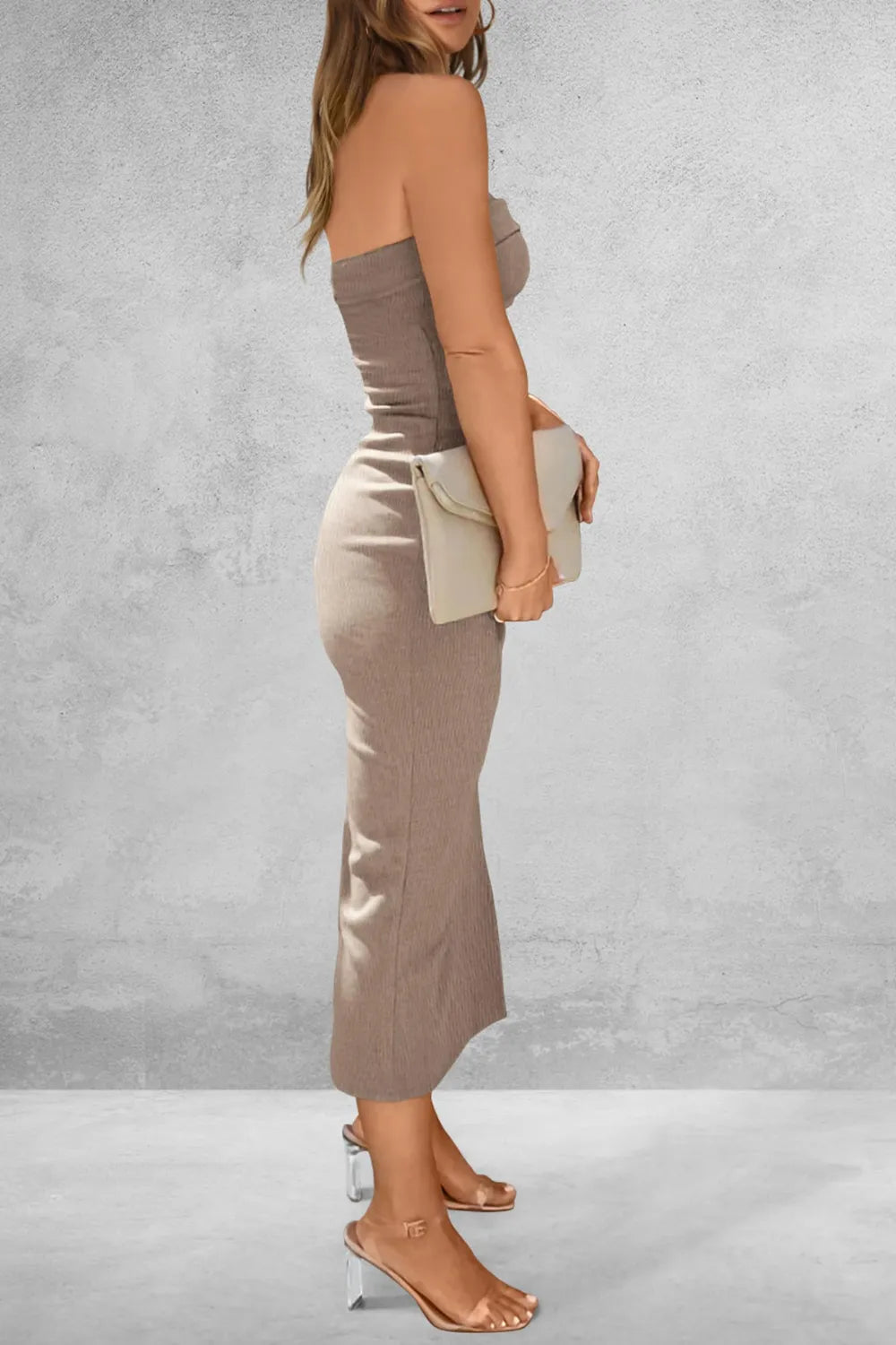 Woman wearing a strapless top and high-waisted pants against a gray background