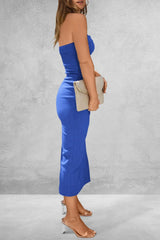 Woman wearing a blue strapless jumpsuit against a gray background