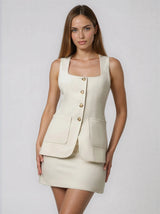 Woman wearing a cream-colored dress with button details on a plain background