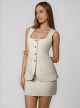Woman wearing a beige sleeveless blazer and skirt set on a white background