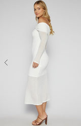 Woman wearing a white off-shoulder dress with long sleeves on a plain background