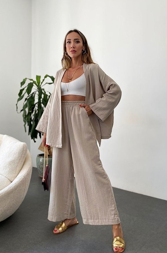 A model wearing the Zafira Pants and Cardigan Two Piece Set in beige, styled for a relaxed yet elegant look.