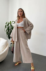 A model wearing the Zafira Pants and Cardigan Two Piece Set in beige, styled for a relaxed yet elegant look.