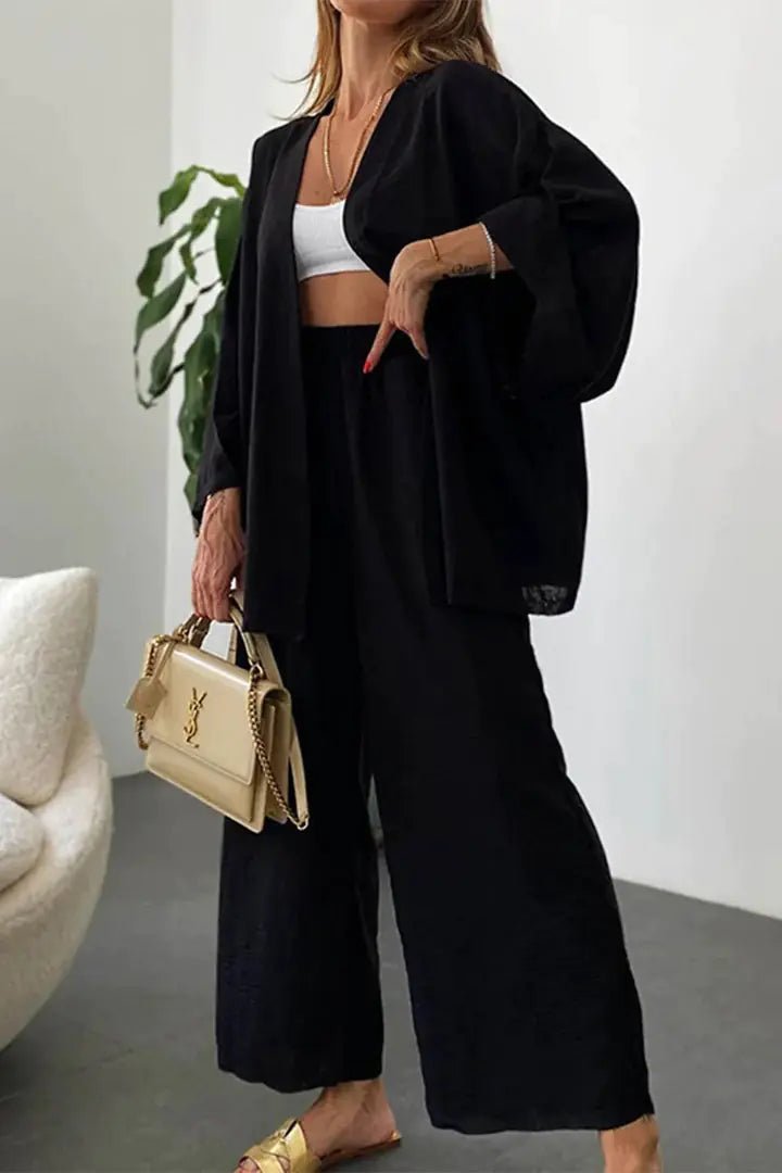 A model wearing the Zafira Pants and Cardigan Two Piece Set in black styled for everyday chic.