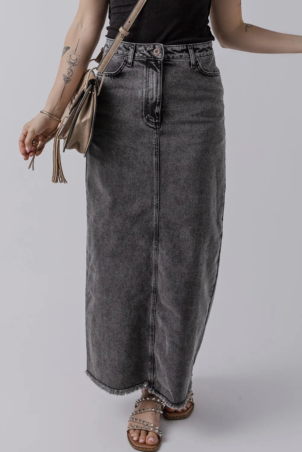 Three-quarter view of model wearing the Zuri Maxi Denim Skirt in Black, paired with a crossbody bag.