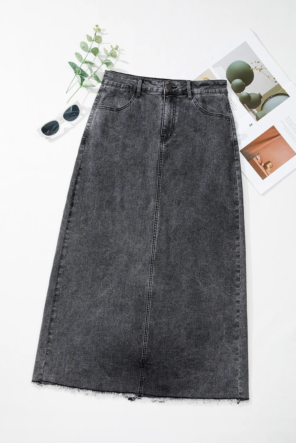 Flat lay of the Zuri Maxi Denim Skirt in Black styled with sunglasses and a phone case.
