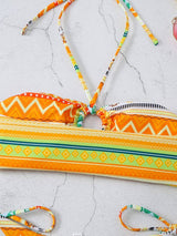 Yellow-orange bikini top and bottoms with tribal print laid flat on white background.