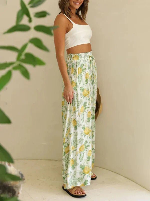 Woman wearing a white crop top and pineapple print pants against a neutral background