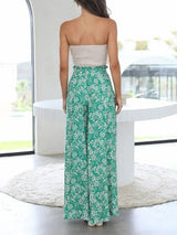 Woman wearing a strapless top and green floral pants in a modern indoor setting