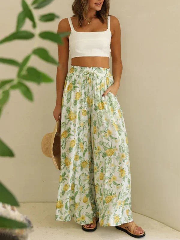 Woman wearing a white crop top and floral wide-leg pants with a neutral background