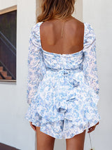 Rear view of the blue Belladonna Floral Playsuit, revealing shirred cuffs and delicate fabric.