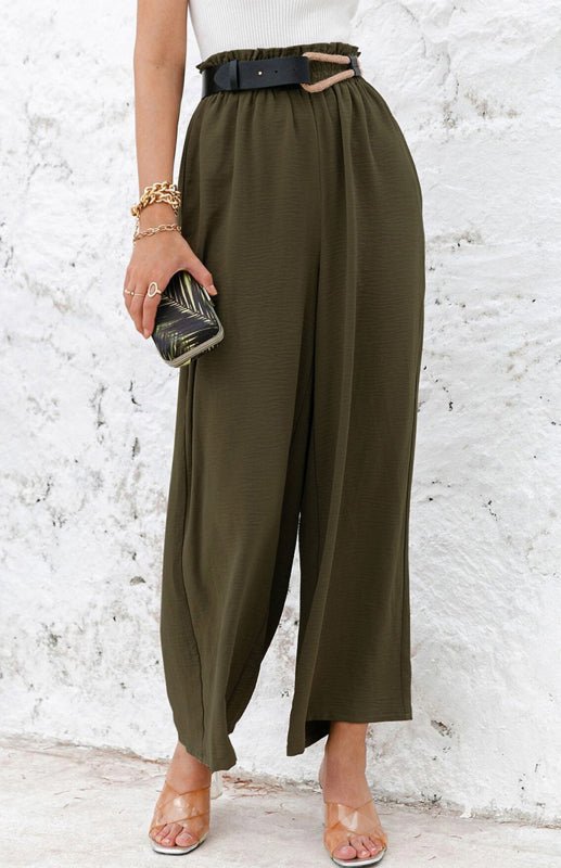 Woman wearing olive green wide-leg pants with a white textured wall background