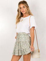 Side view of model in the Ruffle Mini Skirt in green floral print, styled with a white tee.