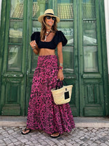 Rose colour variation of floral maxi skirt paired with black top and sun hat, styled for a casual summer stroll.