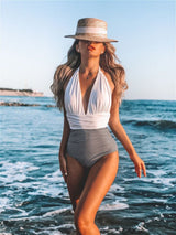 White version of the halter swimsuit worn near ocean, styled with a straw hat.