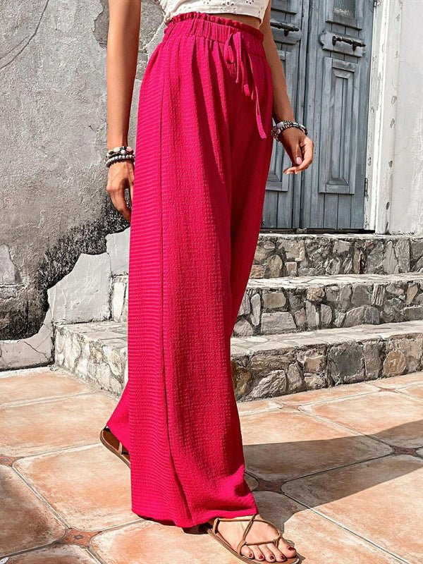 Woman wearing bright pink wide-leg pants standing on stone steps.