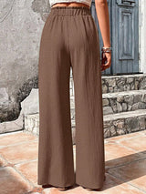 Brown wide-leg pants worn by a Woman standing on stone steps.