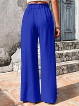 Woman wearing blue wide-leg pants standing on a stone path.