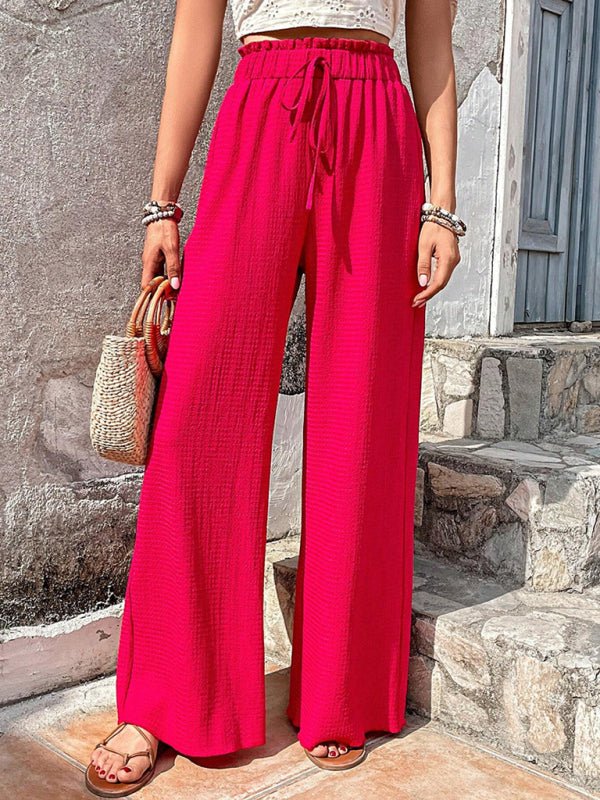 Woman wearing bright pink wide-leg pants standing on stone steps.