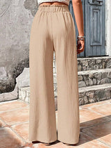 Beige wide-leg pants worn by a woman standing on stone steps.
