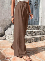 Woman wearing brown wide-leg pants standing on stone steps.