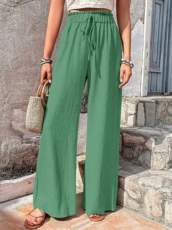 Woman wearing green wide-leg pants standing on stone steps.