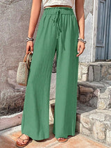 Woman wearing green wide-leg pants standing on stone steps.