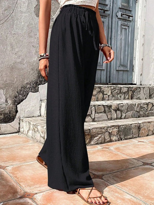 Woman  wearing black wide-leg pants standing on stone steps.