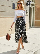 Woman wearing Asymmetric Polka Dot Midi Skirt in black and white print with off-shoulder white top and sandals