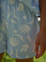 Close-up of shorts showing ruched waistband and light blue summer print.