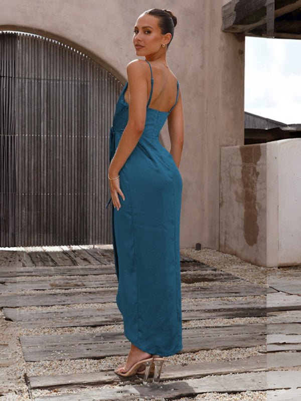 Woman in a teal dress standing on a wooden deck with a neutral wall background