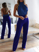 Back view of model in blue version of The Blathin Jumpsuit, highlighting satin fabric and open back.