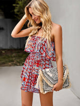 Model holding a clutch and wearing The Freya Strapless Playsuit in boho print for a summer-ready look.