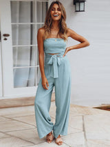 A model poses in The Janisa Jumpsuit in blue, showcasing the relaxed wide-leg fit and shirred bodice with a natural pose.